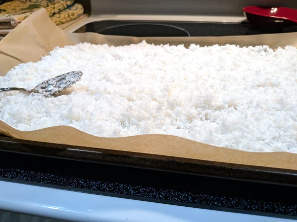 A baking sheet filled with a thick layer of chopped coconut meat.