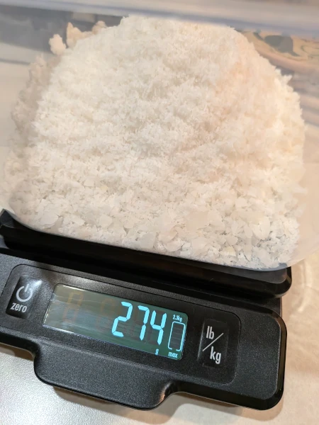 Desiccated coconut meat weighed atop a digital scale, which reads 274 grams