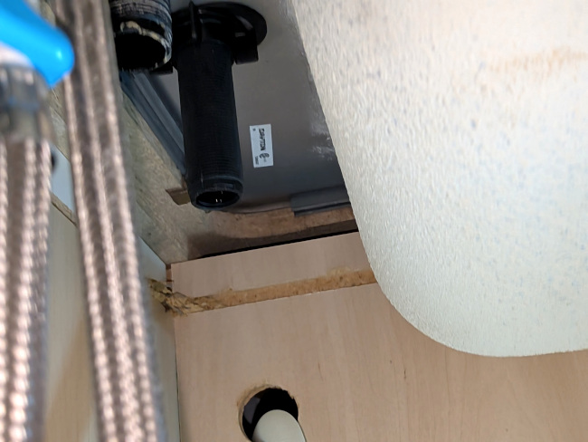 A photo from under the sink, showing the upper edge of the inner cabinet wall and the edge of the sink over top of it extending beyond. Much of the view is blocked by the bowl of the sink.