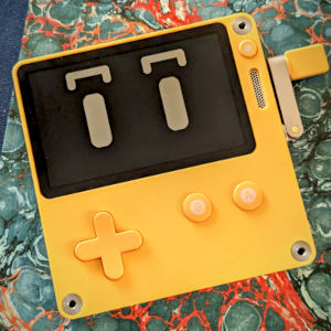 An image of the Playdate handheld game system. Its casing is yellow and its screen displays cute eyes.