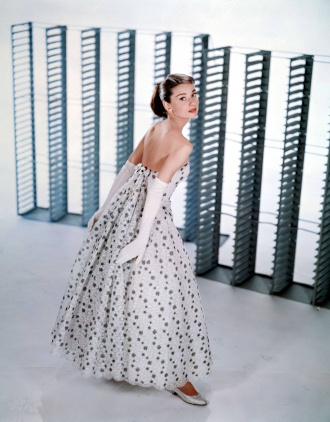 Audrey Hepburn wearing a strapless white dress with black spots and a pair of white gloves, taken from above and behind/to the side
