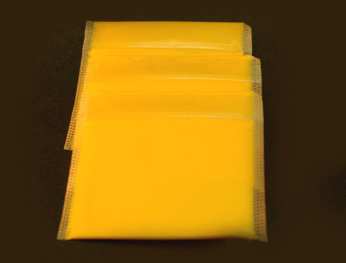 a photograph of three slices of orange American cheese wrapped in plastic