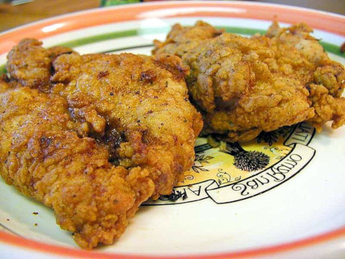 a photograph of two pieces of fried chicken on a decorative plate