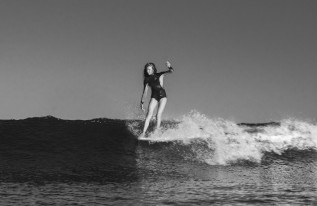 a surfer riding a wave, standing at the front of the board, doing a kind of hang ten maneuver